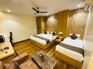 a hotel room with two beds and a couch at Hotel JK palace in Allahābād