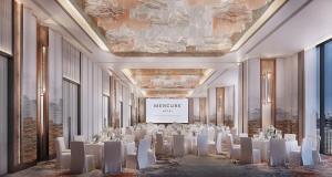 a ballroom with white tables and chairs and a screen at Mercure Bangkok Siam Ratchathewi in Bangkok