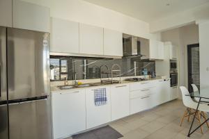 a large kitchen with white cabinets and a table at Ebene City Centre - 2 Bedroom Apartment in Ebene +12 photos