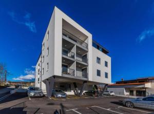 a large white building with cars parked in a parking lot at Deluxe Apartment Bono in Sinj