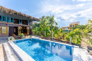 a villa with a swimming pool in front of a building at Wooden chill house in Hoi An