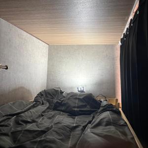 a bed with a black comforter in a room at ゲストハウスヤドカリ in Nanao +4 photos