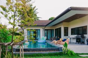 a couple sitting on a couch in front of a house at Villa Panalai in Nakhon Nayok