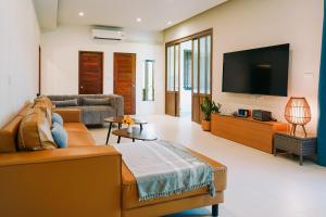 a living room with a couch and a flat screen tv at Villa Panalai in Nakhon Nayok