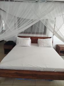 a bed with white sheets and pillows in a room at Castello in Anakao