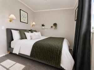 a bedroom with a large bed with white and green at The Nelson Lookout - Mountain Views & City Centre Living in Nelson