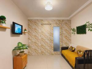 a living room with a yellow couch and a tv at Shore Residences 1 tower D in Manila +4 photos