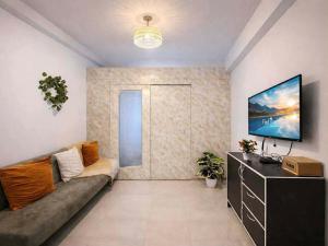 a living room with a couch and a tv at Shore Residences 1 tower D in Manila