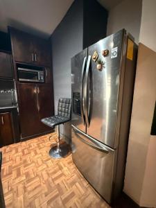 a stainless steel refrigerator in a kitchen with a stool at Casa en Tepic in Tepic