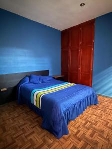 a blue bedroom with a bed and a wooden floor at Casa en Tepic in Tepic