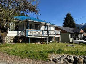 a white house with a blue railing on a porch at Husie by die see in Tahsis