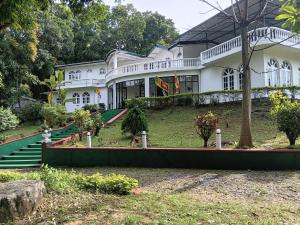 a large white house with stairs in front of it at Royal Mount Hotel in Pussellawa
