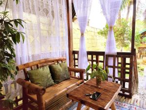 a wooden bench sitting on a porch with a table at Amwani Garden Pool & Kubo in Puerto Princesa City