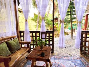 a porch with a table and chairs and curtains at Amwani Garden Pool & Kubo in Puerto Princesa City