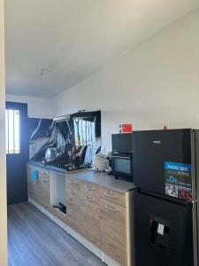 a kitchen with a black refrigerator and wooden cabinets at La Cazatila in Petite Île