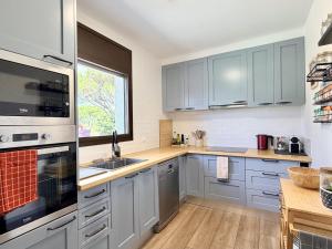 a kitchen with gray cabinets and a window at Villa Pins by Costabravaway in Llagostera