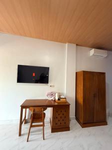 a room with a wooden table and a tv on a wall at Manta Manta Guesthouse in Labuan Bajo