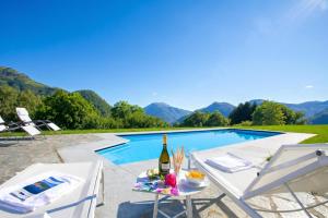 a villa with a pool and a table with a bottle of wine at Villa Intelvi in Castiglione dʼIntelvi
