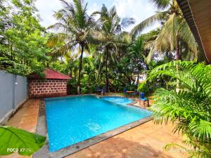 a pool in the backyard of a villa with palm trees at Sarovar Morjim in Morjim