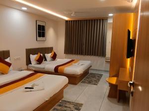 a hotel room with two beds and a television at hotel vistara luxe in Himatnagar