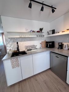 a kitchen with white cabinets and a sink at Casa 26 in Olhão