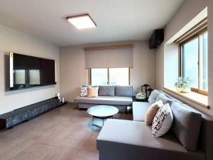 a living room with a couch and a flat screen tv at KUON Onomichi - クオン尾道 in Onomichi