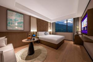 a hotel room with a bed and a tv at Manxin Hotel Nanjing Mufu Mountain in Nanjing