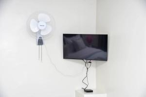 a white fan and a tv on a white wall at The Premier Comfort in Nairobi