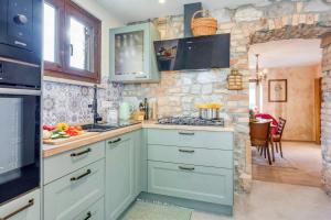 a kitchen with blue cabinets and a stone wall at Vila Leonarda with Terrace and Garden - Happy Rentals in Miren
