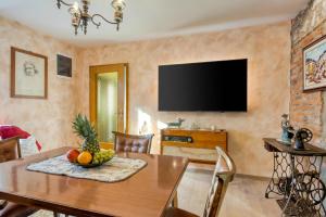 a dining room with a table and a flat screen tv at Vila Leonarda with Terrace and Garden - Happy Rentals in Miren
