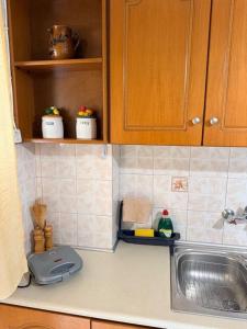 a kitchen counter with a sink and wooden cabinets at KATERINA's House in Preveza +60 photos