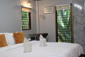 a bedroom with two beds and a table and a window at Charlotte place in El Nido