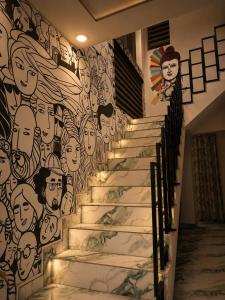 a stairwell with a mural of people on the wall at Padmora in Trivandrum +1 photo