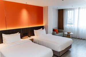 two beds in a hotel room with an orange wall at Jiuding Joy Hotel in Kathmandu +153 photos