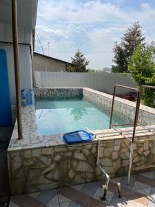 a swimming pool with a stone wall and a poolvisorangering at Жилье на природе с бассейном in Tashkent