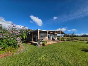 a house with a pavilion in a field of grass at Hideaway Falls Rustic Farm House in Ravenshoe