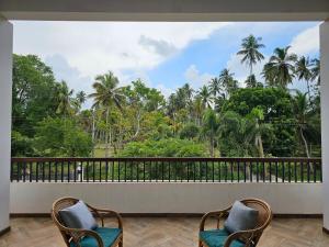 two chairs on a balcony with a view of trees at Sunrise Staycation in Katuneriya