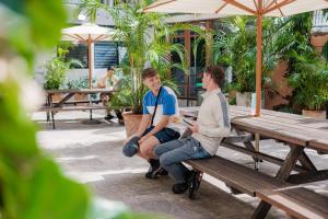 two young men sitting on a wooden bench at Bunk Surfers Paradise 18-35 Backpacker Hostel in Gold Coast