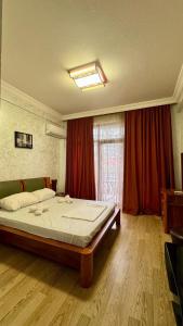 a bedroom with a large bed with red curtains at Antika Hotel in Batumi