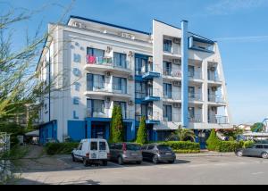 a large white building with cars parked in a parking lot at Hotel Nadia in Primorsko