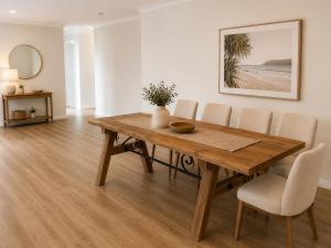 a dining room with a wooden table and chairs at Charming & Spacious 5 Bedroom Bayside House with Pool in Birkdale