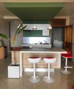 a kitchen with two stools and a counter in a kitchen at Suite confortable avec vue imprenable in Punaauia