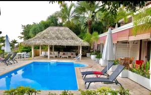 a pool with chairs and umbrellas next to a building at Suite confortable avec vue imprenable in Punaauia
