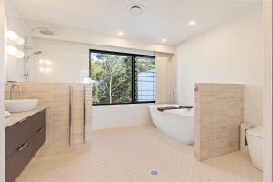 a bathroom with a tub and a sink and a toilet at Perfectly Pambula in Pambula Beach +35 photos