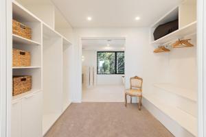 a hallway with white walls and a chair at Perfectly Pambula in Pambula Beach