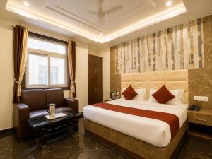 a hotel room with a large bed and a chair at Hotel Hyfa Continental in Lucknow