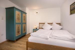 a bedroom with a bed with white sheets and a blue cabinet at Haus Anna in Kirchberg in Tirol