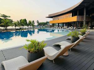 a swimming pool with lounge chairs and a building at Endless Summer Seafront - 1BR Beach Resort Condo in San Juan