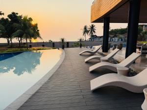 a row of white lounge chairs next to a swimming pool at Endless Summer Seafront - 1BR Beach Resort Condo in San Juan