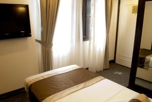 um quarto com uma cama, um espelho e uma janela em The Inn at Temple Street em Singapura